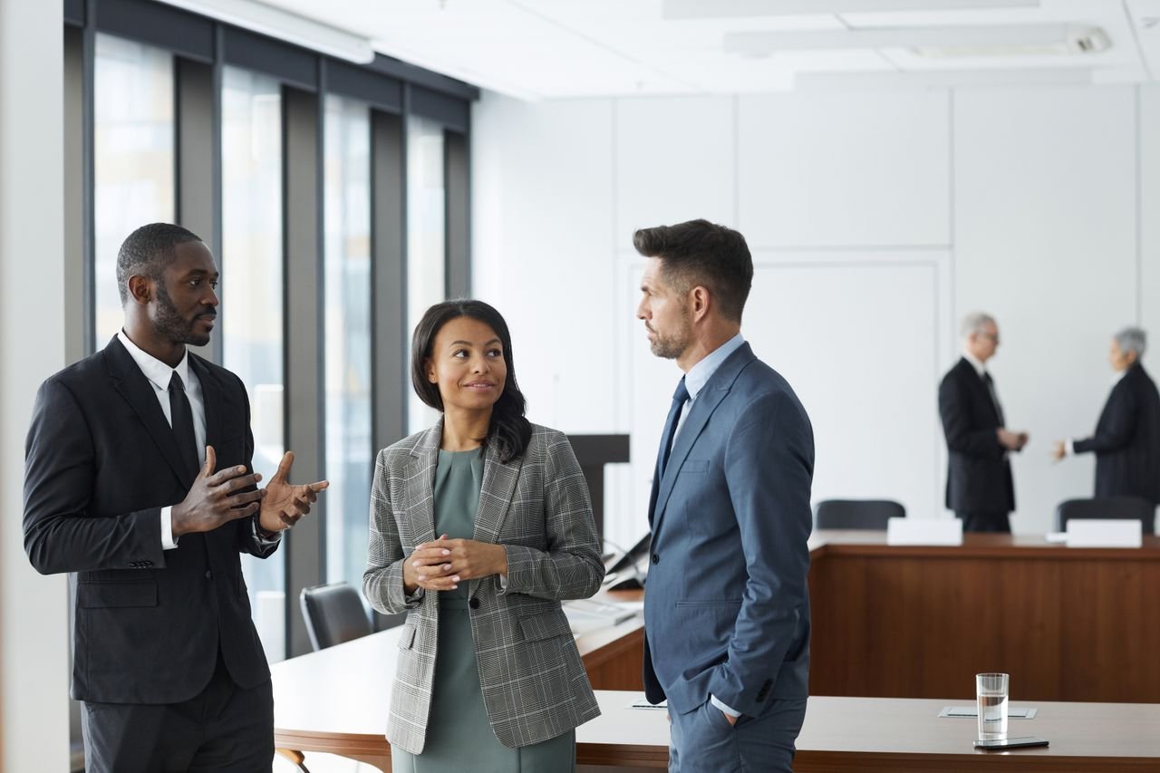 Group of professionals engaged in conversation in a modern office setting.